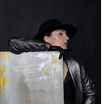 Person wearing a black hat and silver outfit against a dark background